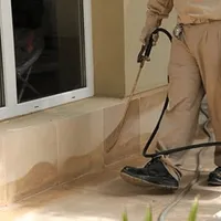 General pest control technician spraying exterior perimeter around a home in Detroit, MI