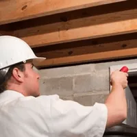Termite inspection technician checking a basement wall and framing for termite activity in Detroit, MI